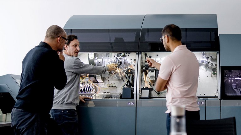 Four men are participating in a training session, working together on a G+D product in an office setting