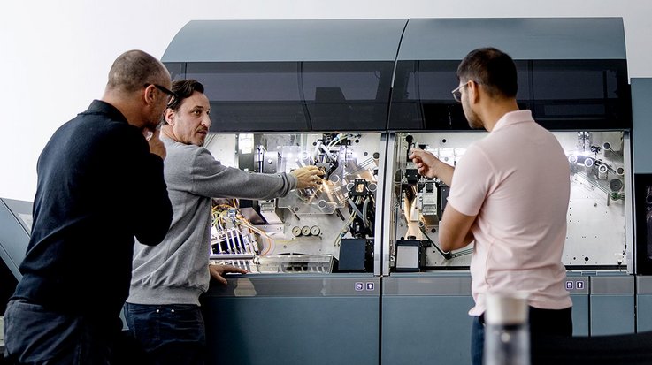 Four men are participating in a training session, working together on a G+D product in an office setting