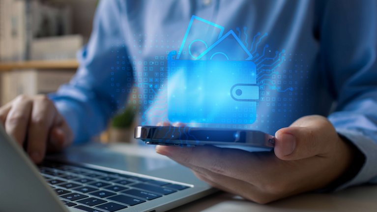 Close up of a person at the laptop who also holds a cell phone in their hand