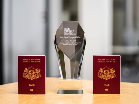 Two frontally photographed Latvian passports with Veridos Award in between