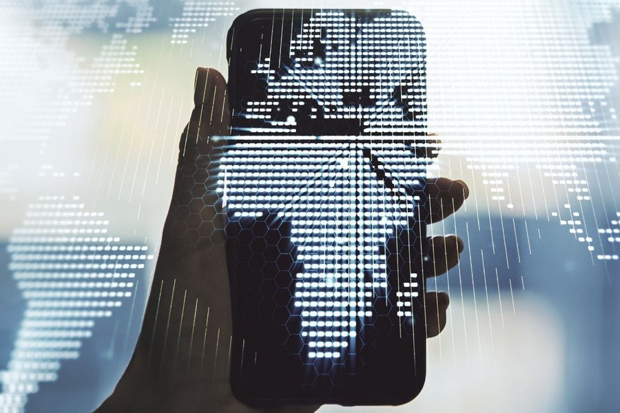Hand holding a smartphone with a digital world map showing Africa in the center
