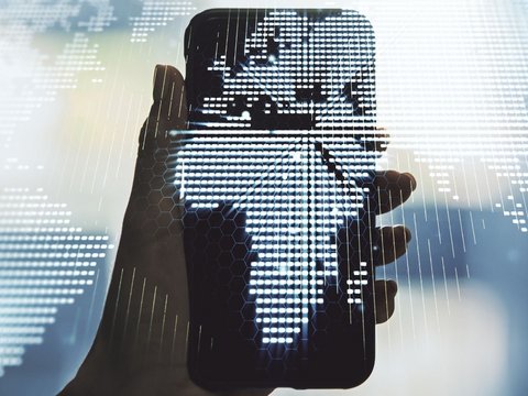 Hand holding a smartphone with a digital world map showing Africa in the center