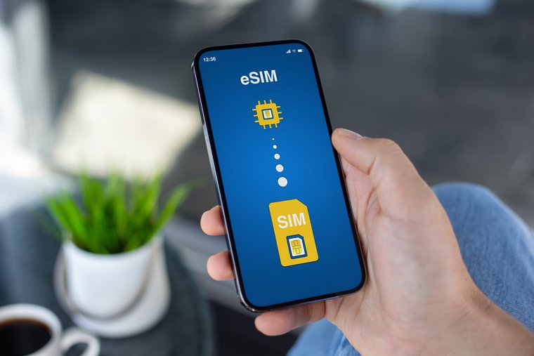 A hand holds a smartphone displaying an eSIM setup screen with icons representing the transition from traditional SIM to eSIM.