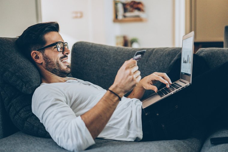 Man at home buying online on his laptop with a card 