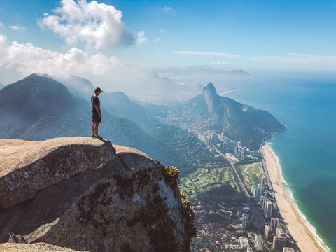 A man stands on the top of Pedra da Gávea watching the views over Rio de Janeiro, Brazil