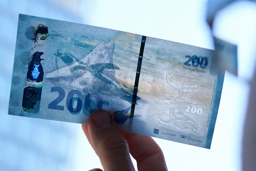 Man holding a banknote against the light to see the security features