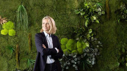 Woman in front of a green plant wall