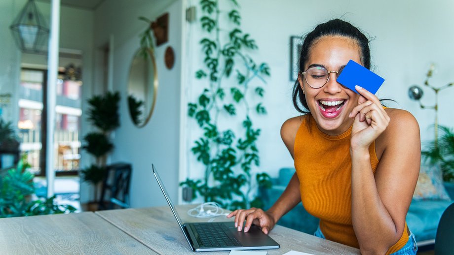 Portrait of a young woman holding a credit card in front of a laptop for online shopping