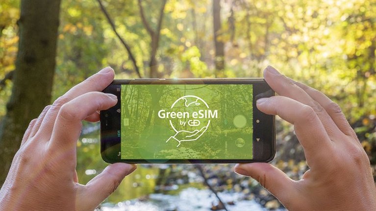 Smartphone with G+D Green eSIM logo in front of wooded background