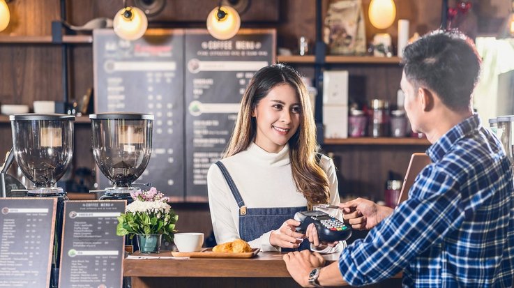 A man pays contactless with a credit card in a café