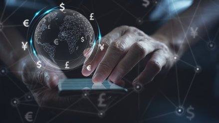 A man operates a smartphone, above it floats a digital globe and financial symbols