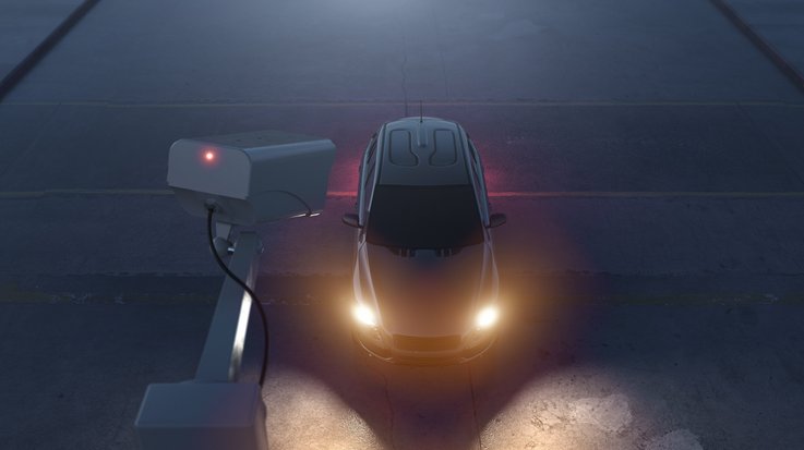 A car with headlights on is filmed by a CCTV camera