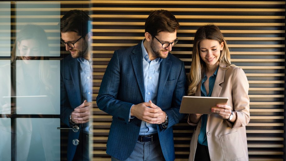 Two people work concentratedly on a tablet computer in a modern office.