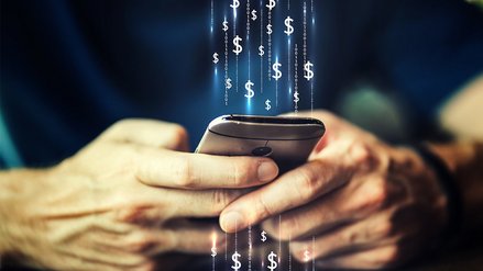 Someone operates a smartphone, digital currency symbols hover above it
