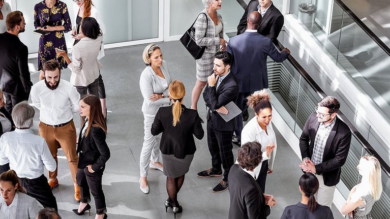 Many people stand together in groups and talk
