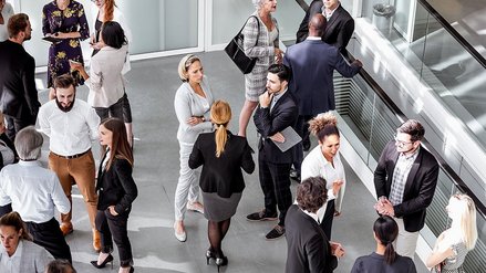 Many people stand together in groups and talk