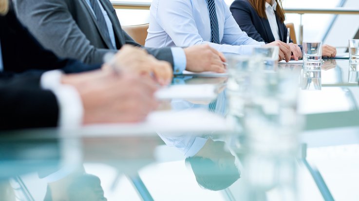 four people sitting at a table and taking notes