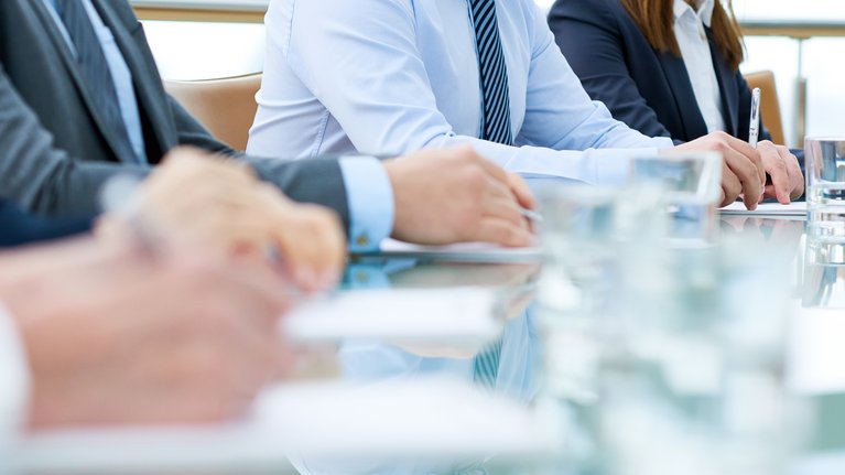 four people sitting at a table and taking notes
