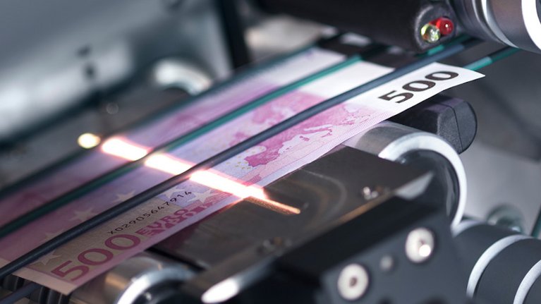 A 500€ bill is screened and inspected in a machine