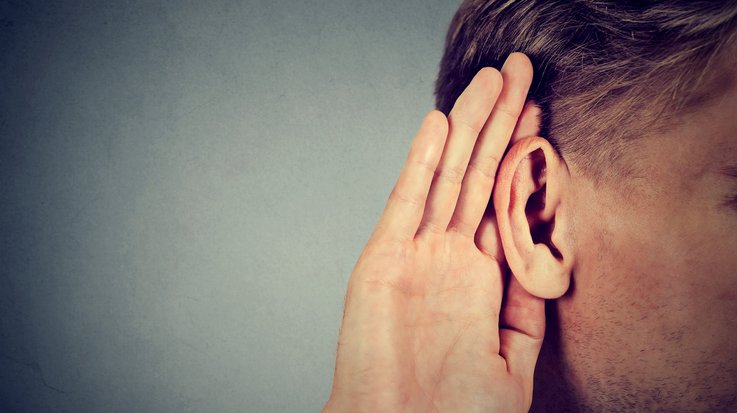 a man holds a hand behind his ear