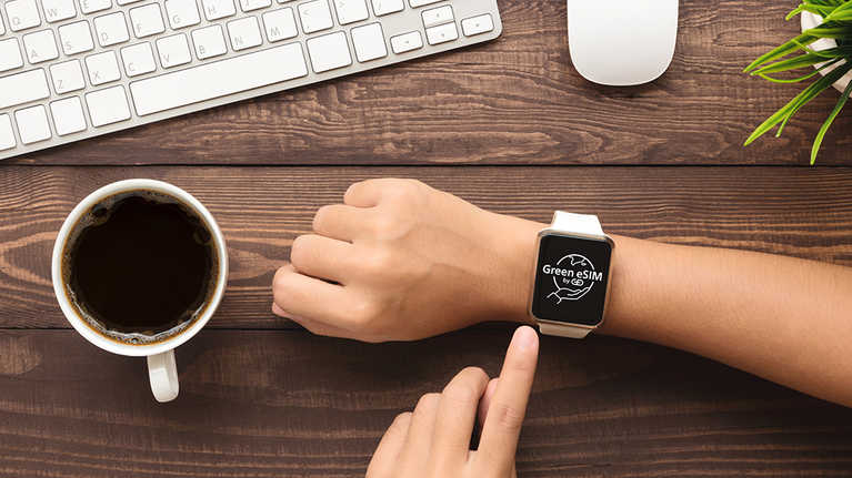 A person operates a smartwatch with the inscription "Green eSIM by G+D".